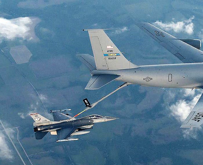 A KC-135 Stratotanker aerial refueling plane services a large jet while in the air.